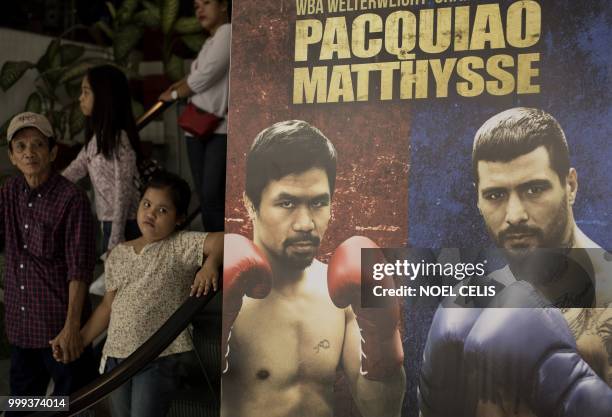 Shoppers ride an escalator past an advertising board that features the boxing match between Manny Pacquiao of the Philippines and Argentina's Lucas...