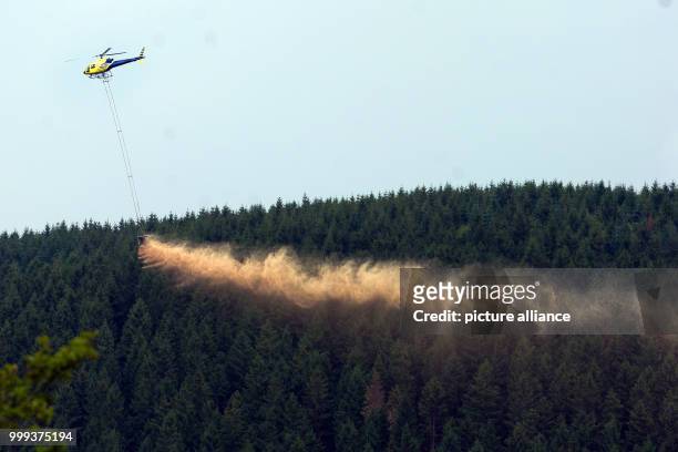 Helicopter scattering lime from a silo hanging from a hook over a stretch of forest near the Federal Highway 241 in the Harz mountains near to...
