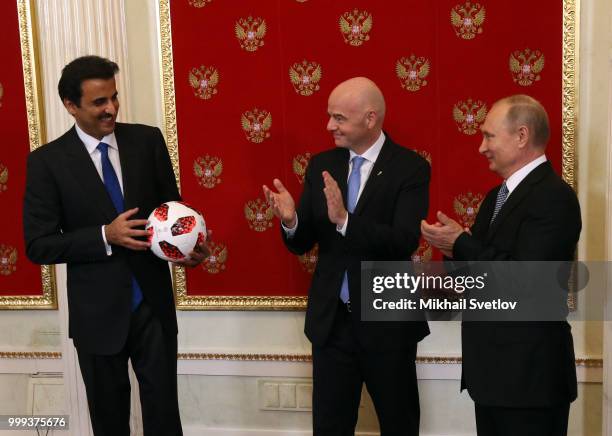 Russian President Vladimir Putin passes symbolic FIFA World Cup Baton to Qatari Emir Tamim bin Hamad al-Thani as FIFA President Gianni Infantino...