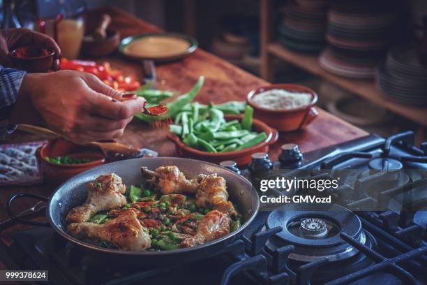 preparing chicken paella with green beans, peas and paprika - gmvozd stock pictures, royalty-free photos & images