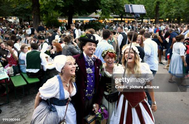 July 2018, Germany, Munich: Women dressed as maids beside a man dressed as Ludwig II during the Kocherlball at the Chinesischer Turm . Every year,...