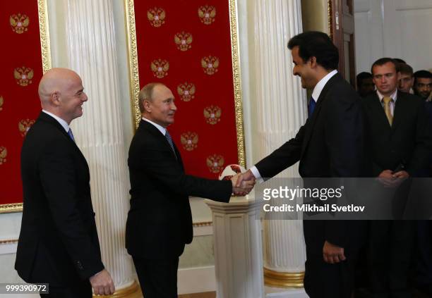 Russian President Vladimir Putin greets Qatari Emir Tamim bin Hamad al-Thani as FIFA President Gianni Infantino looks on during their ceremony at the...