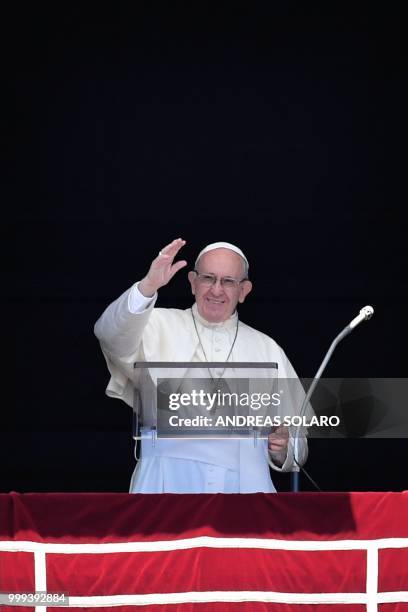 Pope Francis waves to the crowd from the window of the apostolic palace overlooking St Peter's square during the Sunday Angelus prayer, on July 15,...