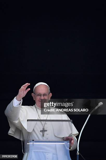 Pope Francis waves to the crowd from the window of the apostolic palace overlooking St Peter's square during the Sunday Angelus prayer, on July 15,...