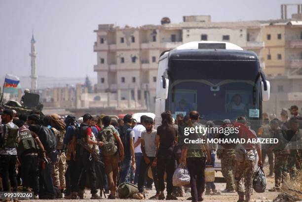 Syrian rebels and their families stand by buses to be evacuated from Daraa city, on July 15 as Syrian government forces heavily bombed the...