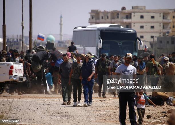 Syrian rebels and their families stand by buses to be evacuated from Daraa city, on July 15 as Syrian government forces heavily bombed the...