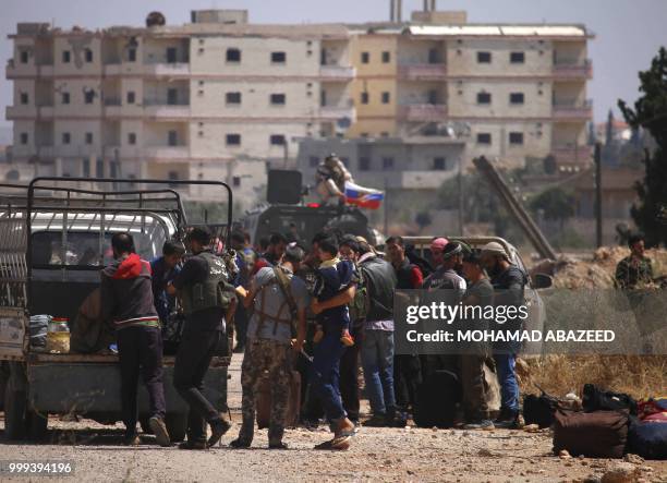 Syrian rebels and their families stand by vehicles to be evacuated from Daraa city, on July 15 as Syrian government forces heavily bombed the...