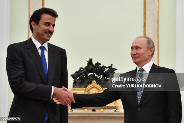 Emir of Qatar Sheikh Tamim bin Hamad Al-Thani shakes hands with Russian President Vladimir Putin during their meeting at the Kremlin in Moscow on...