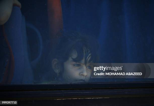 Syrian girl looks out from a bus window during rebels and their families evacuation from Daraa city, on July 15 as Syrian government forces heavily...