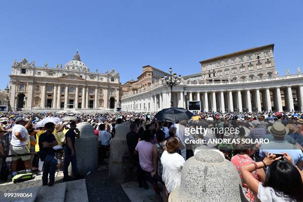 People listen to the speech of Pope Francis speaking from the window of the apostolic palace overlooking St Peter's square during the Sunday Angelus...