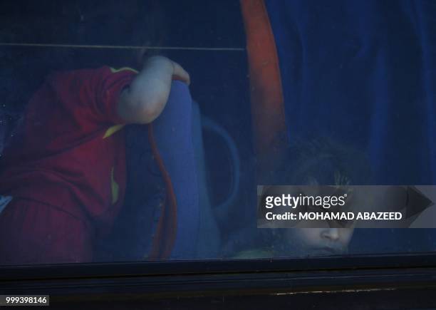 Syrian girl looks out from a bus window during rebels and their families evacuation from Daraa city, on July 15 as Syrian government forces heavily...