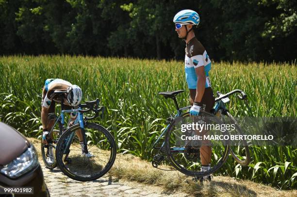 France's Alexis Vuillermoz stands by the stage's first cobblestone section after handing a wheel to France's Romain Bardet who suffered a puncture,...