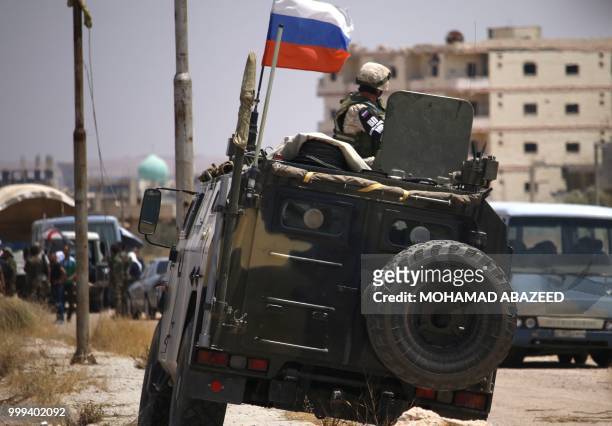 Russian soldier on his armoured vehicle watches Syrian rebels during evacuation from Daraa city, on July 15 as Syrian government forces heavily...
