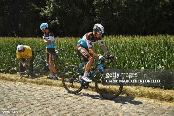 France's Alexis Vuillermoz changes wheel in the stage's first cobblestone section after handing his wheel to France's Romain Bardet who suffered a...