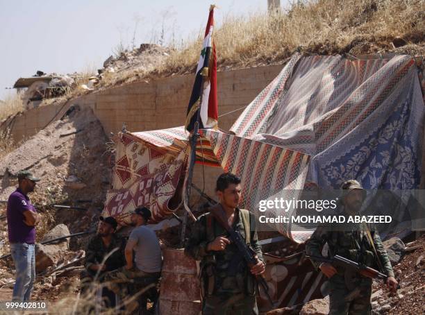 Syrian regime soldiers at a checkpoint watch Syrian rebels during evacuation from Daraa city, on July 15 as Syrian government forces heavily bombed...