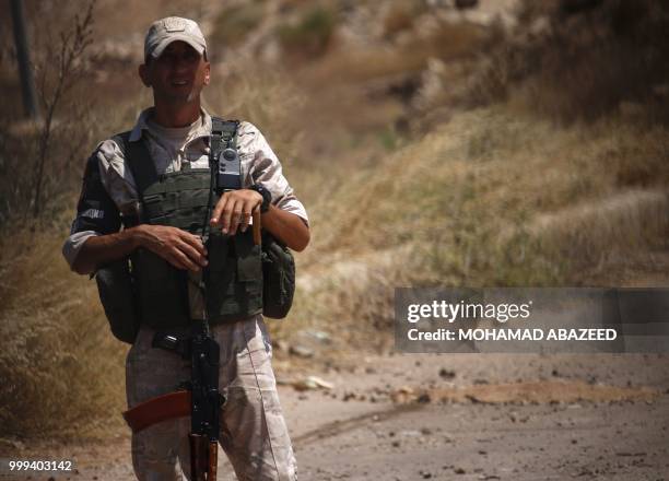 Russian soldier looks at Syrian rebels during evacuation from Daraa city, on July 15 as Syrian government forces heavily bombed the neighbouring...