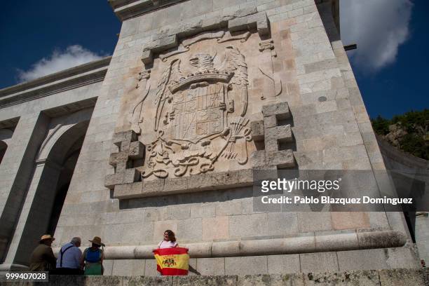 Far right-wing supporter holds a pre-constitutional Spanish flag under a Spanish coat of arms from Franco's period during a gathering at El Valle de...