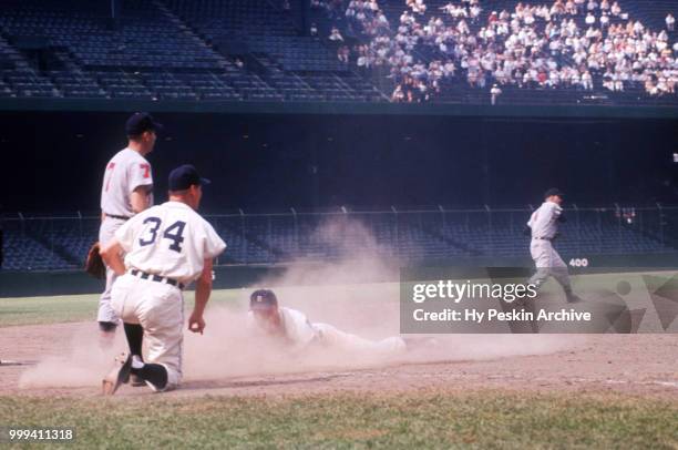 Third base coach Billy Hitchcock of the Detroit Tigers shows Eddie Yost to slide as shortstop George Strickland of the Cleveland Indians throws to...