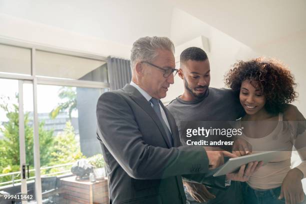 real estate agent showing a property to an african american couple - real estate agent stock pictures, royalty-free photos & images