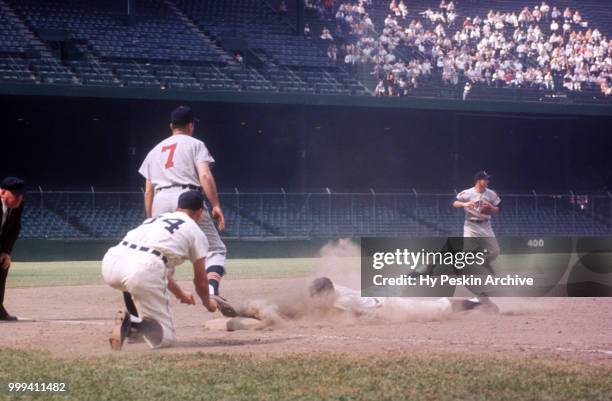 Third base coach Billy Hitchcock of the Detroit Tigers shows Eddie Yost to slide as shortstop George Strickland of the Cleveland Indians throws to...