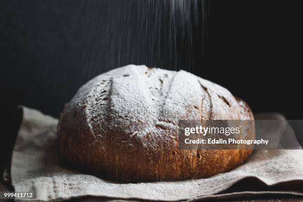 the bread is being sprinkled with flour - round loaf stock pictures, royalty-free photos & images