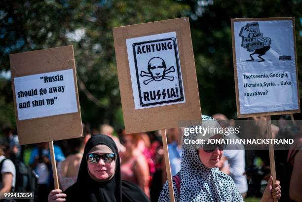 Veiled protesters hold placards during the so-called "Helsinki Calling" march towards the Senate Square to defend the human rights, freedom of speech...