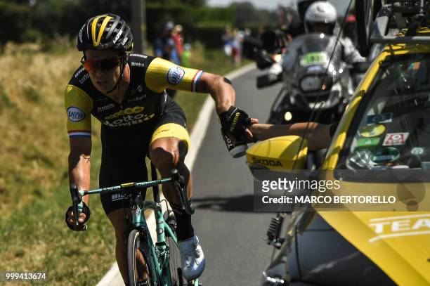 Netherlands' Dylan Groenewegen, his left knee injured after crashing, picks a water bottle as he catches up with the pack during the ninth stage of...