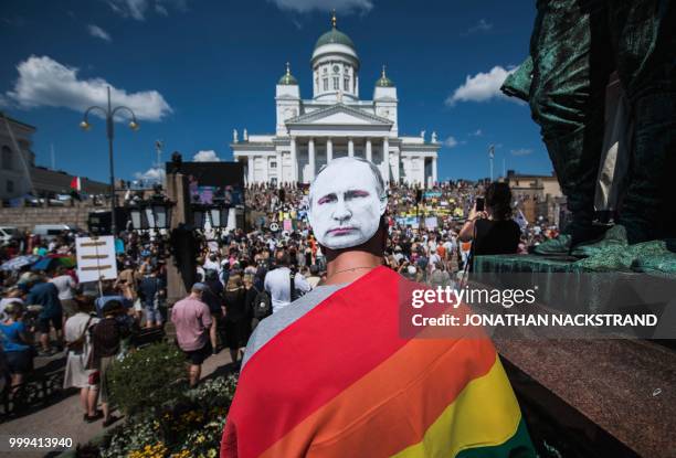 Protester wears a mask bearing a portrait of Russian President Vladimir Putin as protesters gather on the Senate Square at the end of the so-called...