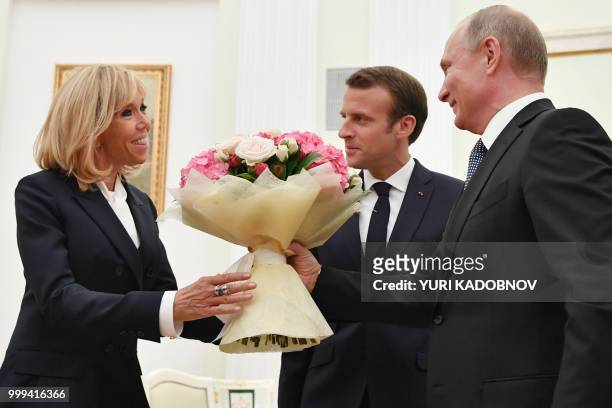 Russian President Vladimir Putin offers flowers to Brigitte Macron , wife of French President Emmanuel Macron during their meeting at the Kremlin in...
