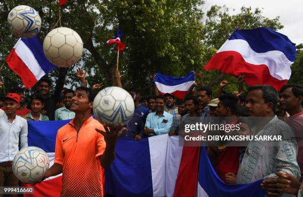 Indian fans of the French football team wave French national flags as a juggler performs ahead of the FIFA 2018 World Cup final match in the French...