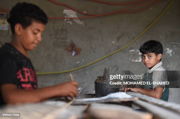 Egyptian boy Abbas Ali looks on as he works at a shop specialised in seashell wood inlays in the Saqyat al-Manqadi village in the Egyptian Nile Delta...