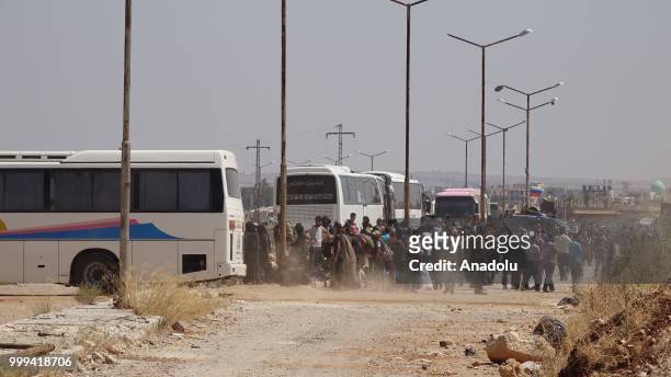 Syrian citizens get on buses to leave Syrias southwestern Daraa province with the 1st convoy on July 15, 2018. The convoy of 15 buses carried 700...