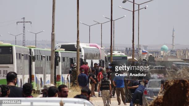 Syrian citizens get on buses to leave Syrias southwestern Daraa province with the 1st convoy on July 15, 2018. The convoy of 15 buses carried 700...