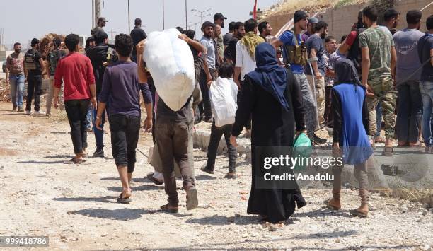 Syrian citizens are seen with their belongings as they wait to leave Syrias southwestern Daraa province with the 1st convoy on July 15, 2018. The...