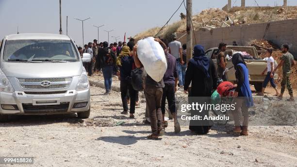 Syrian citizens are seen with their belongings as they wait to leave Syrias southwestern Daraa province with the 1st convoy on July 15, 2018. The...