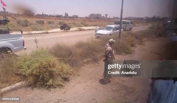 Russian soldier stands guard as Syrian citizens leave Syrias southwestern Daraa province with the 1st convoy on July 15, 2018. The convoy of 15 buses...