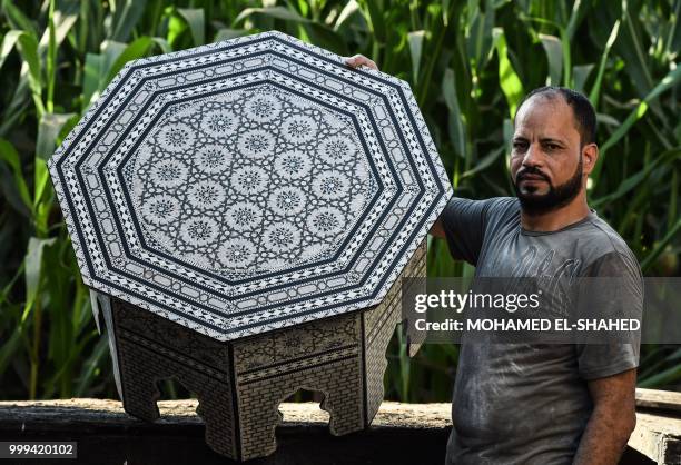 Egyptian Azouz Brik shows a finished table at a shop specialised in seashell wood inlays in the Saqyat al-Manqadi village in the Egyptian Nile Delta...