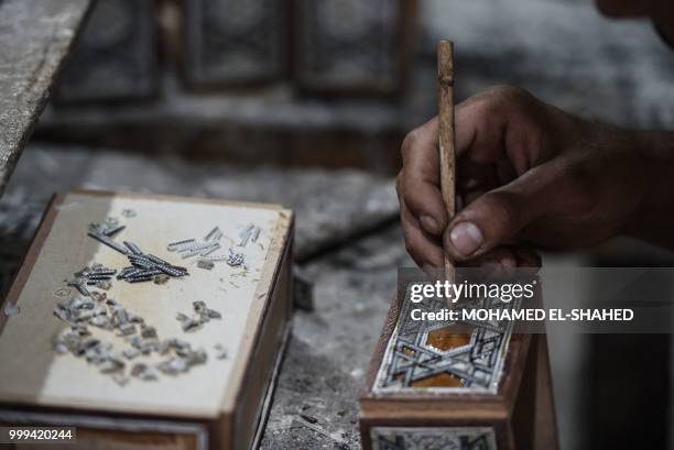 An Egyptian labourer works at a shop specialised in seashell wood inlays in the Saqyat al-Manqadi village in the Egyptian Nile Delta province of...