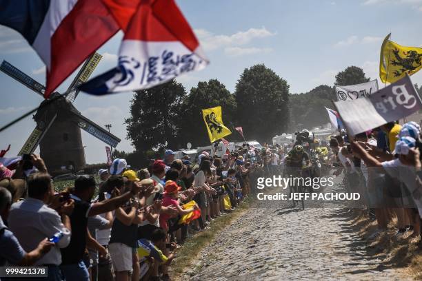 Spectators waving French flags cheer France's Damien Gaudin leading a two-men breakaway through a cobblestone section during the ninth stage of the...