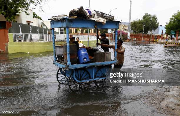 Indian vendor pushes his cart along a flooded road after heavy rain showers in Ajmer, in the Indian state of Rajasthan, on July 15, 2018.