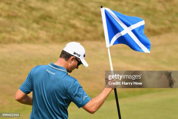Justin Rose of England holds the pin flag on hole one during day four of the Aberdeen Standard Investments Scottish Open at Gullane Golf Course on...