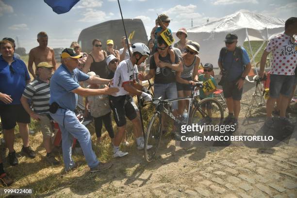 Poland's Michal Kwiatkowski picks up his bicycle after crashing during the ninth stage of the 105th edition of the Tour de France cycling race...