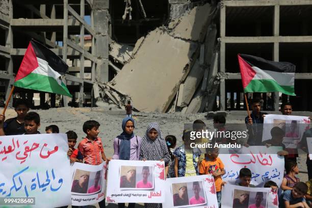 Palestinian children gathering in front of the building which was pounded by Israeli fighter jets and holding pictures of Palestinian children Amir...