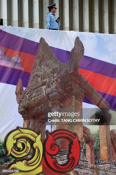 Cambodian police stand guard above a picture of the Preah Vihear temple during a ceremony at the Olympic national stadium in Phnom Penh on July 15,...