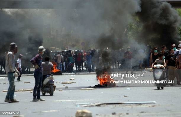 Protesters burn tyres during a demonstration against unemployment and a lack of basic services, in the southern Iraqi city of Basra on July 15, 2018....