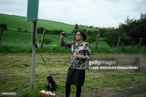 Woman watches as the motorcade carrying US President Donald Trump drives to Glasgow Prestwick Airport, in Maybole, Scotland on July 15 at the...