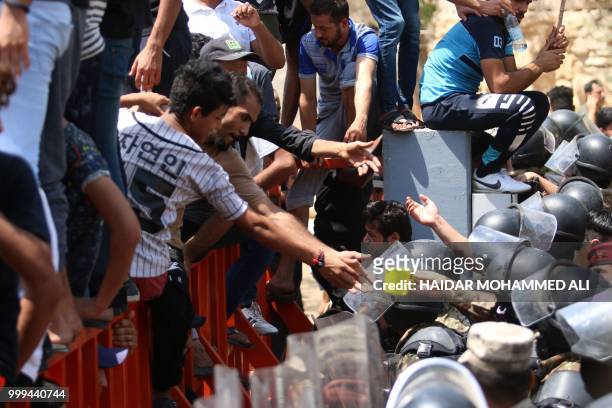 Member of the Iraqi security forces receives water from a protester during a demonstration against unemployment and a lack of basic services in the...