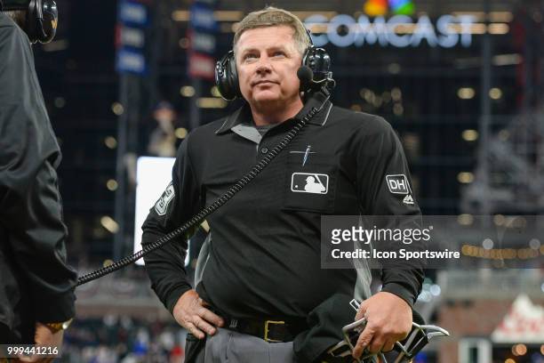 Home plate umpire Greg Gibson listens to the instant replay umpires via digital connection during the game between the Braves and the Phillies on...