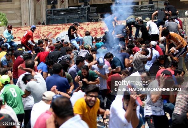 Protesters cringe as Iraqi security forces fire tear gas during a demonstration against unemployment and a lack of basic services, in the southern...