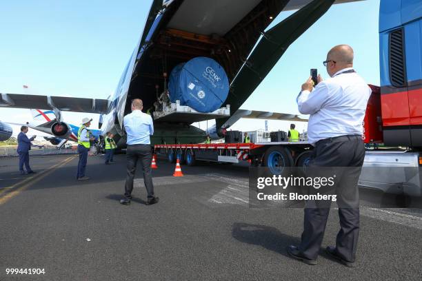 Attendees take photographs during a demonstration of a GEnx jet engine being loaded onto a Volga-Dnepr Group air cargo aircraft during preparations...